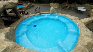 A round outdoor pool surrounded by natural rock formations and seating areas.