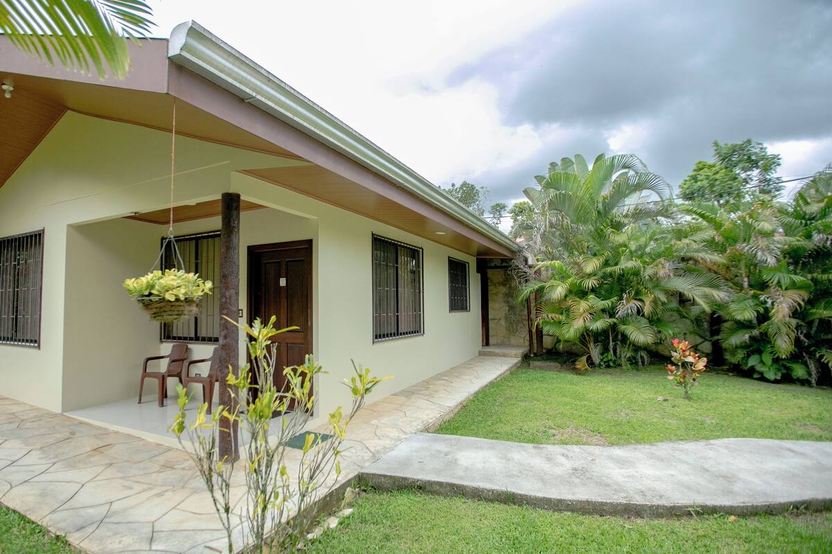 A single-story house with a covered porch, a stone pathway, and a well-maintained lawn.