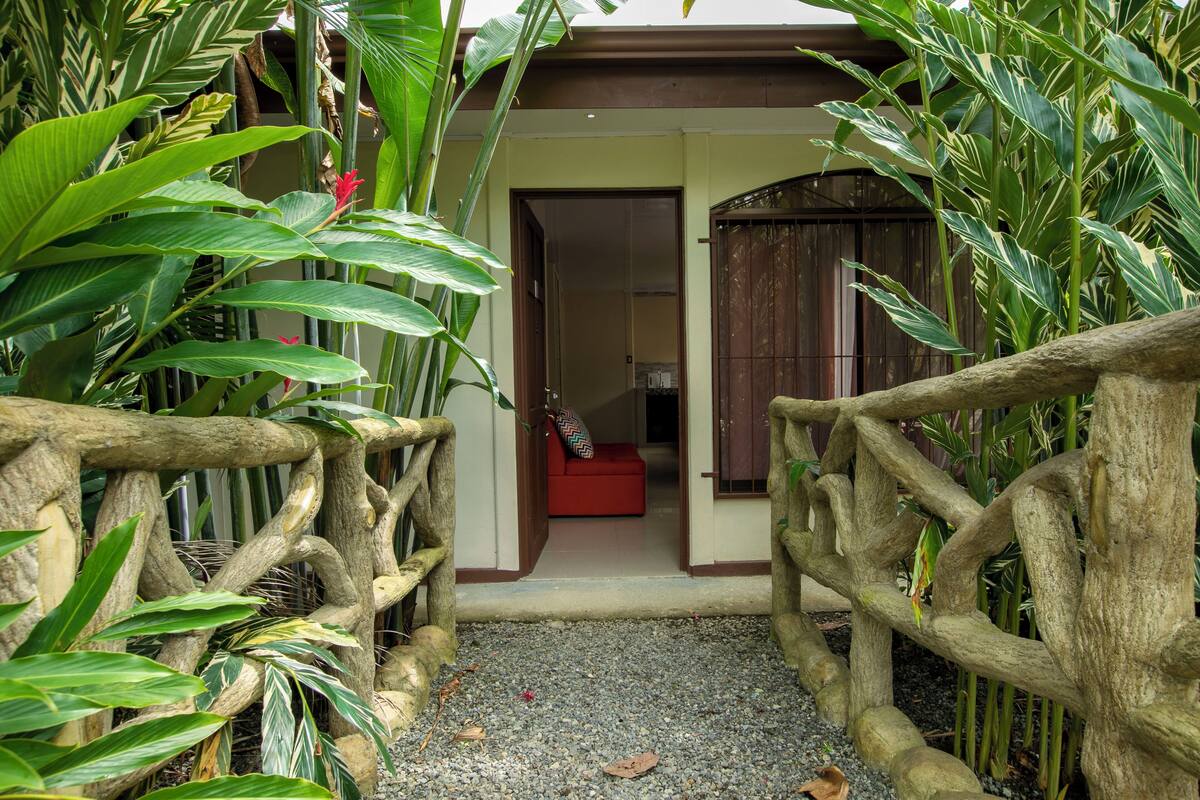 A wooden gate leading to a room with a red sofa and a view of a building through an open door.