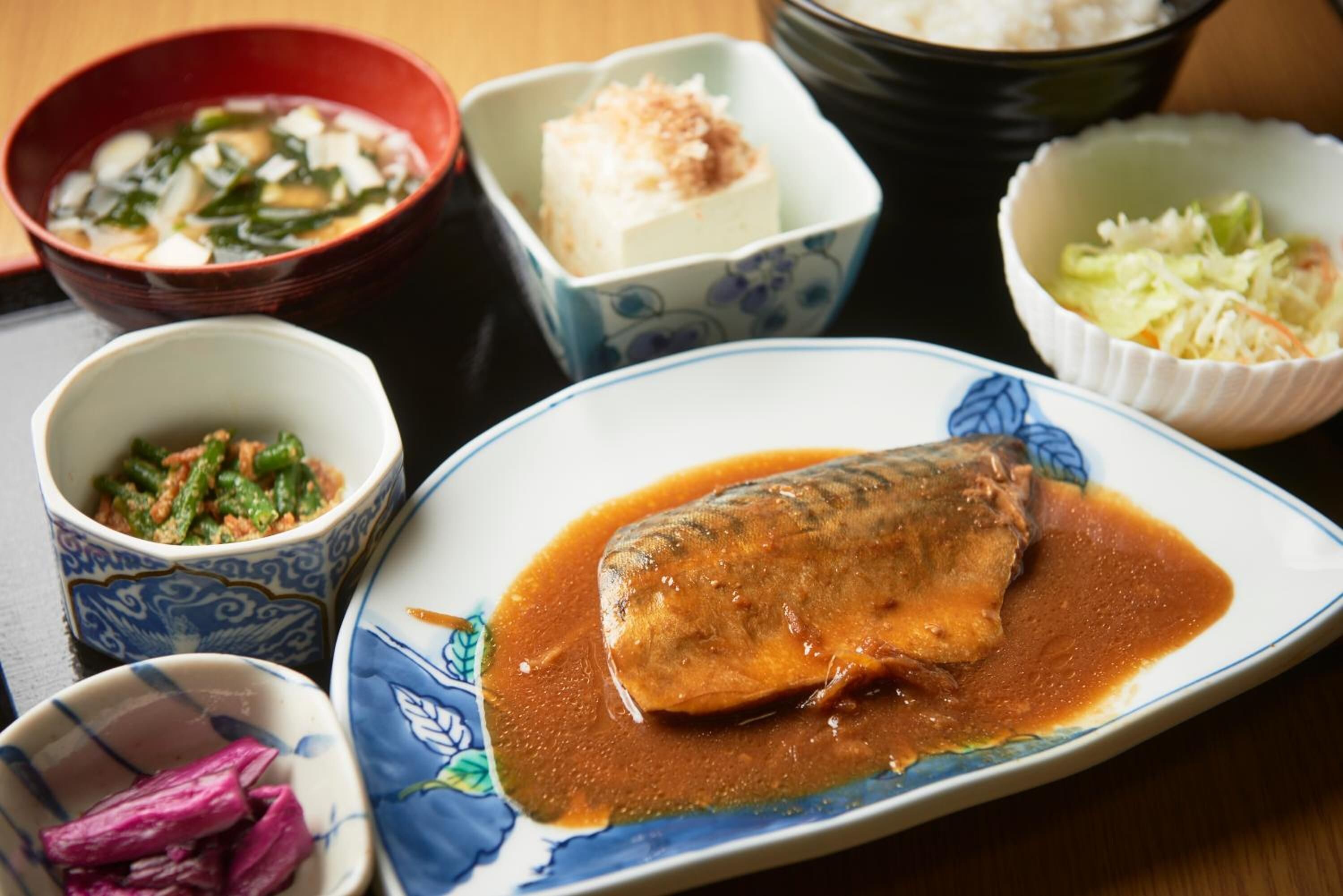 A variety of dishes including a fish in sauce, tofu, and other side dishes.