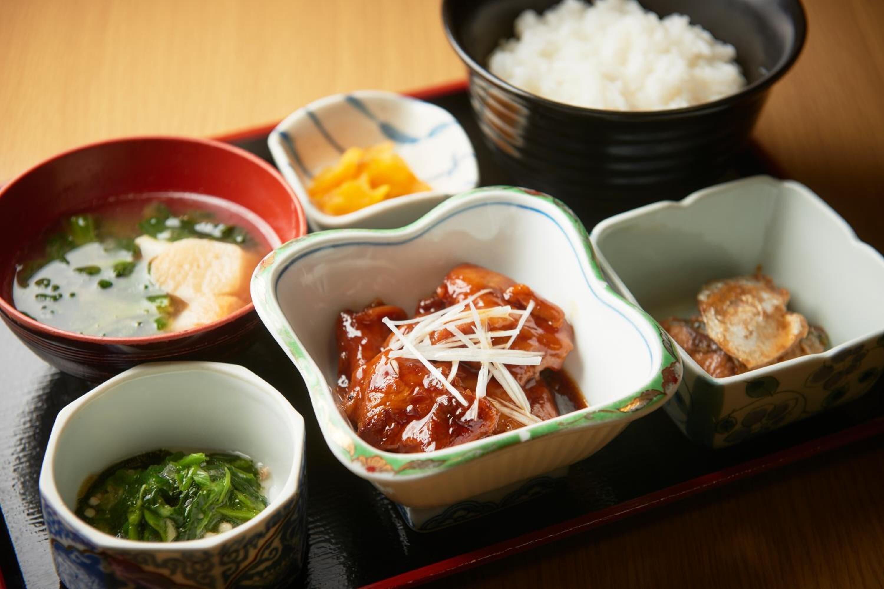 A traditional Japanese meal with various dishes including rice, soup, and meat.