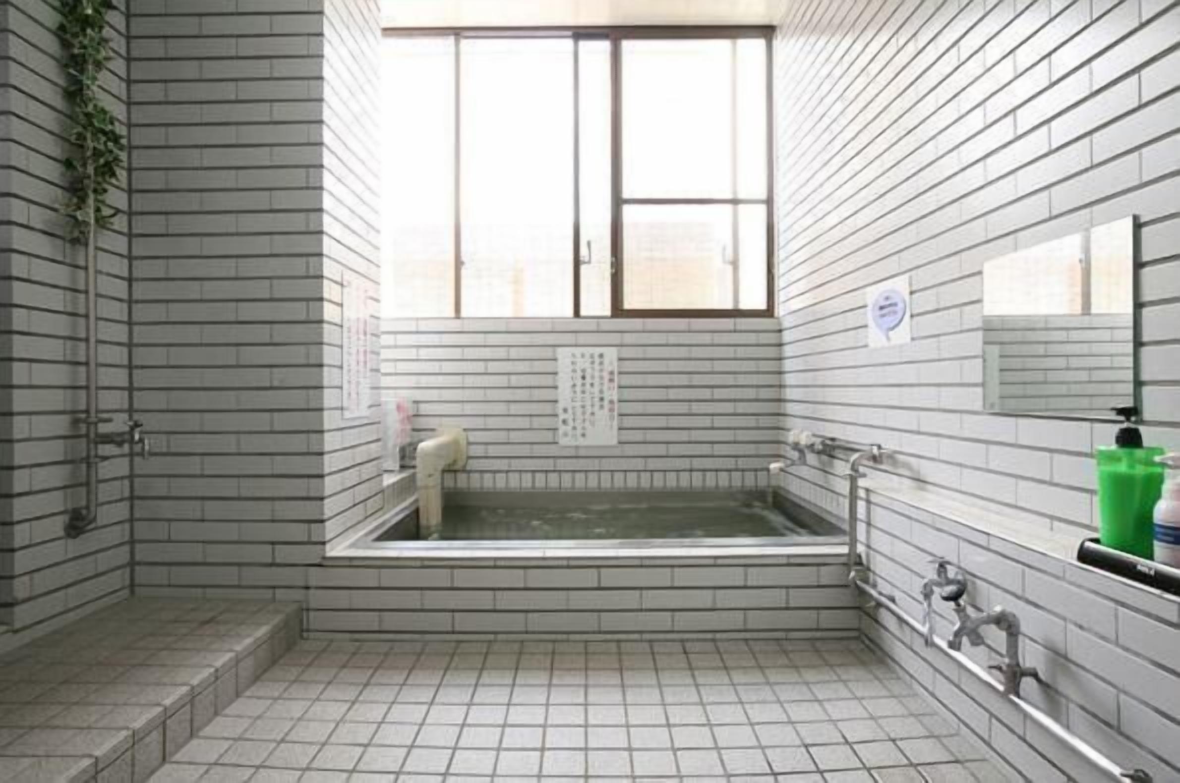 Un baño con bañera, ventana y paredes de azulejos.