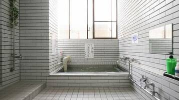 Un baño con bañera, ventana y paredes de azulejos.