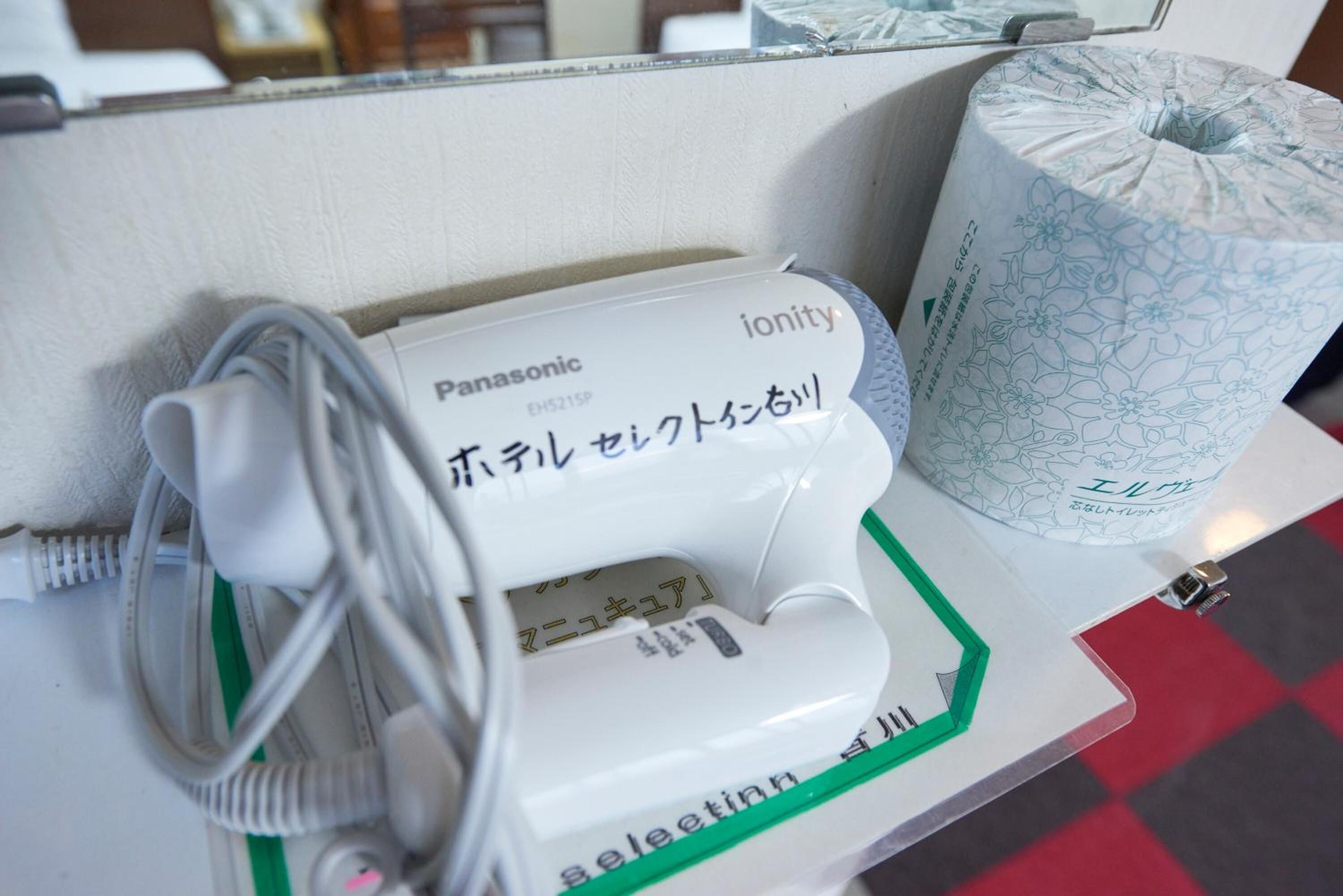 Een Panasonic ionity apparaat, een oplaadkabel en een roll keukenpapier met bloemendesign op een tafel.