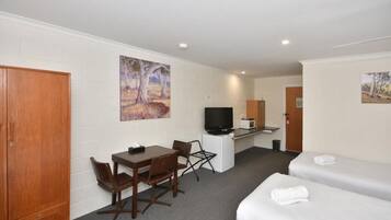 Una camera d'albergo con un letto, una scrivania con una sedia, una televisione e un forno a microonde.