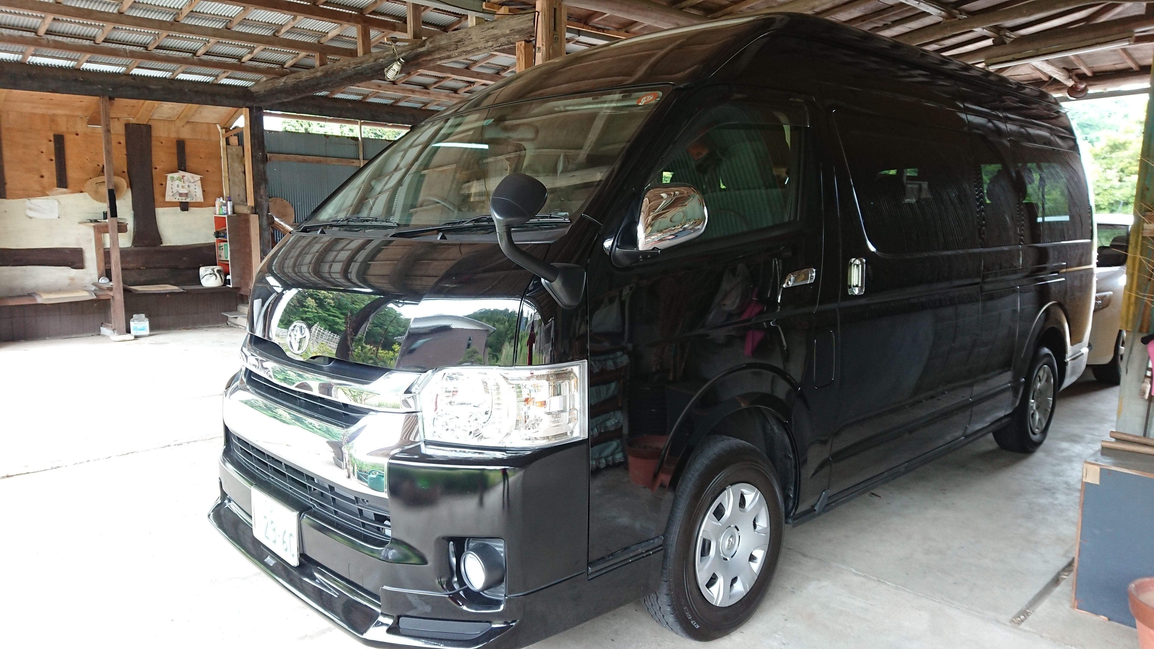 A black van parked inside a covered area with a wooden ceiling and a concrete floor.