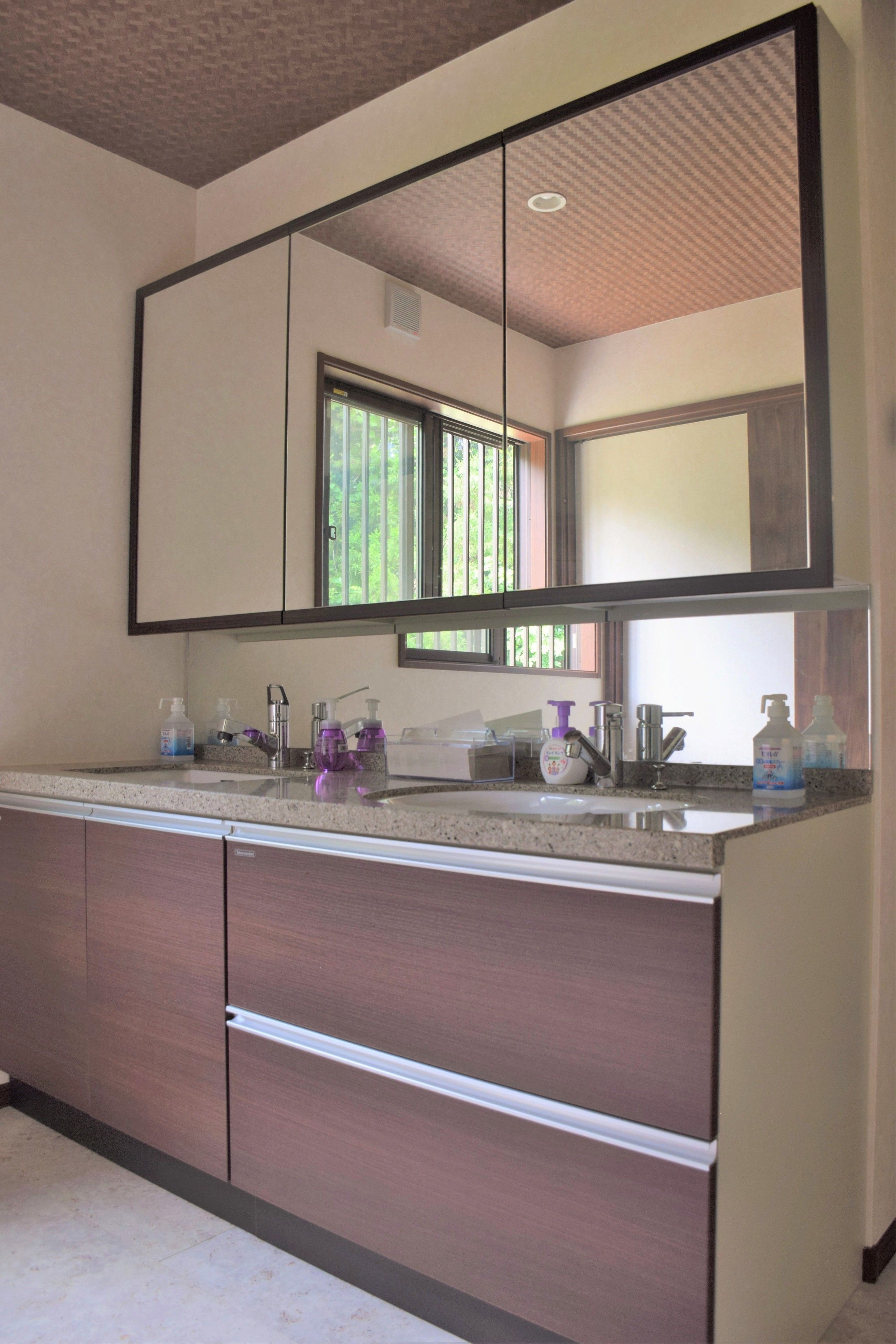 A modern bathroom with a large mirror, a sink, and a window.