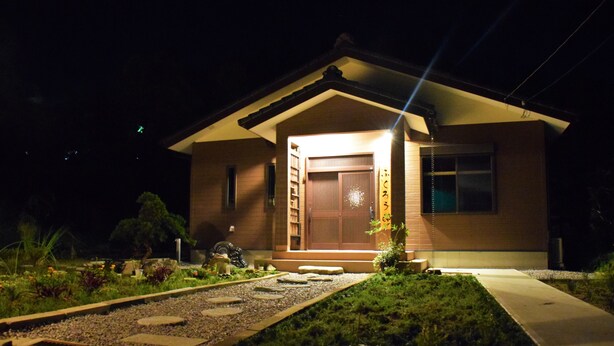 Une maison avec une porte en bois et un petit jardin à l’avant.
