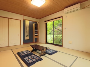 A traditional Japanese room with tatami flooring, a sliding door, a window with a view of greenery, and a low wooden table. - Japanese style hotel FUKUROU TEI (Sosa)