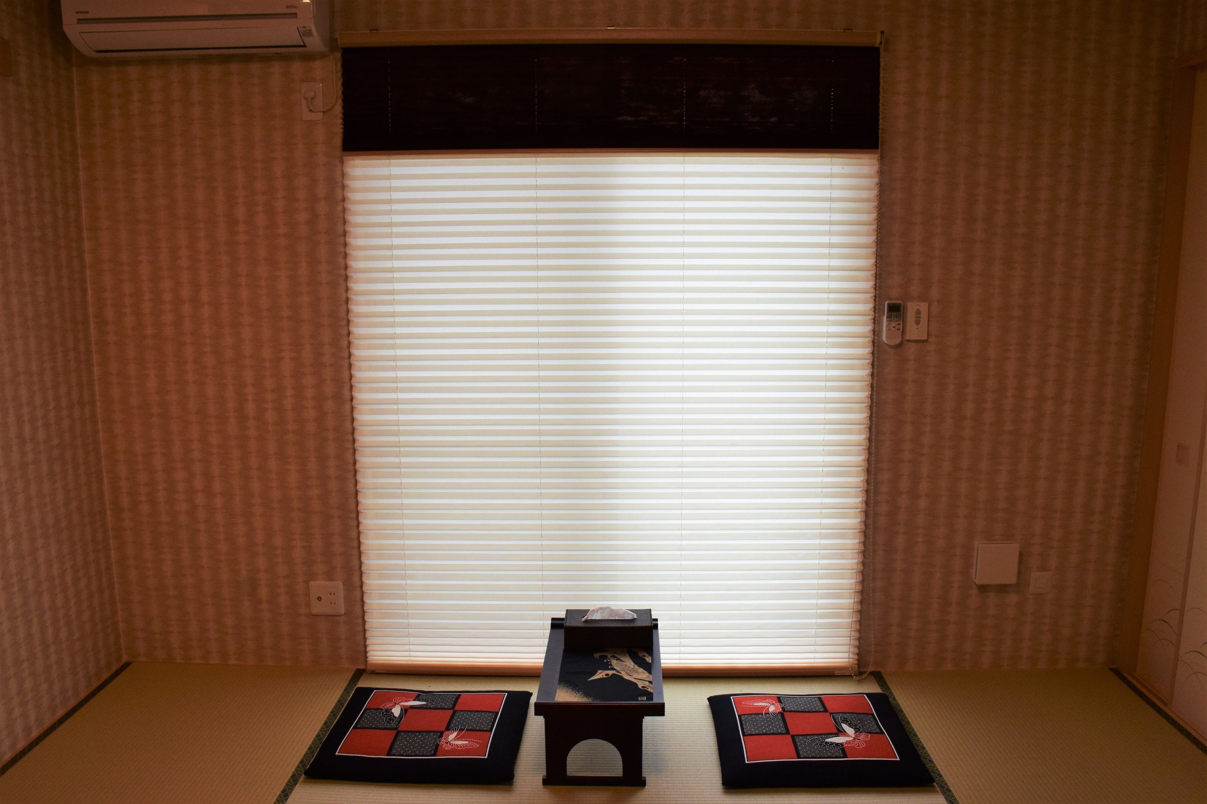 Una stanza con pavimento in tatami, un paravento scorrevole tipo shoji e un piccolo tavolo di legno con un oggetto decorativo.