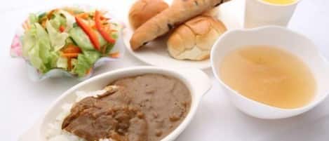 A meal consisting of rice, a meat dish, a salad, rolls, and a soup bowl.