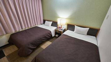 Una habitación de hotel con dos camas, una mesita de noche con lámpara y una ventana con cortinas.