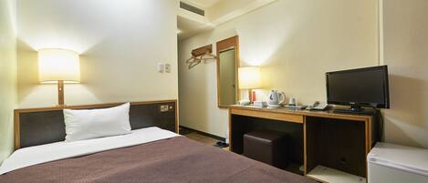 A hotel room with a bed, a desk with a computer, a television, and a mirror.