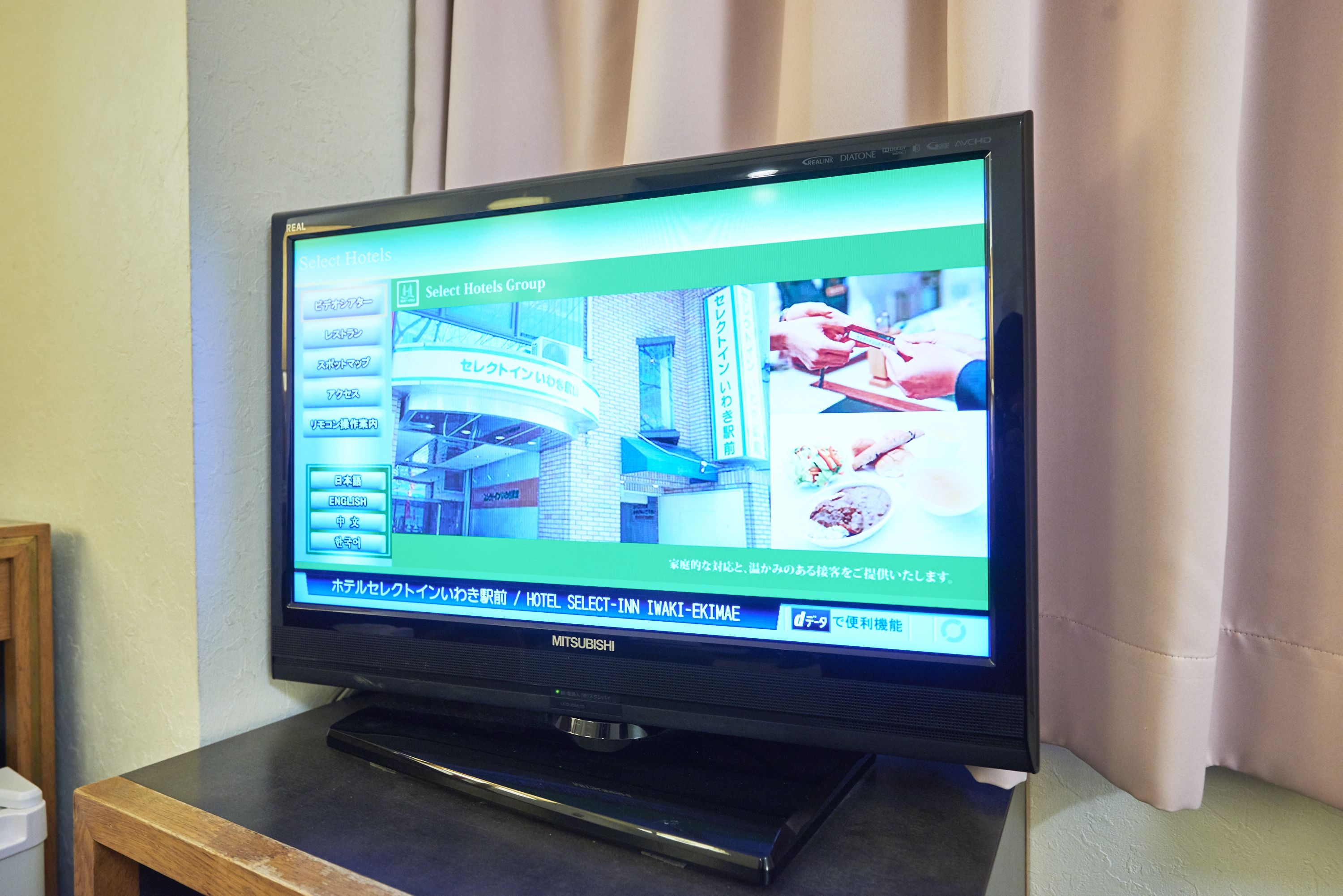 A television displaying a hotel website interface with options for hotel selection and language settings.