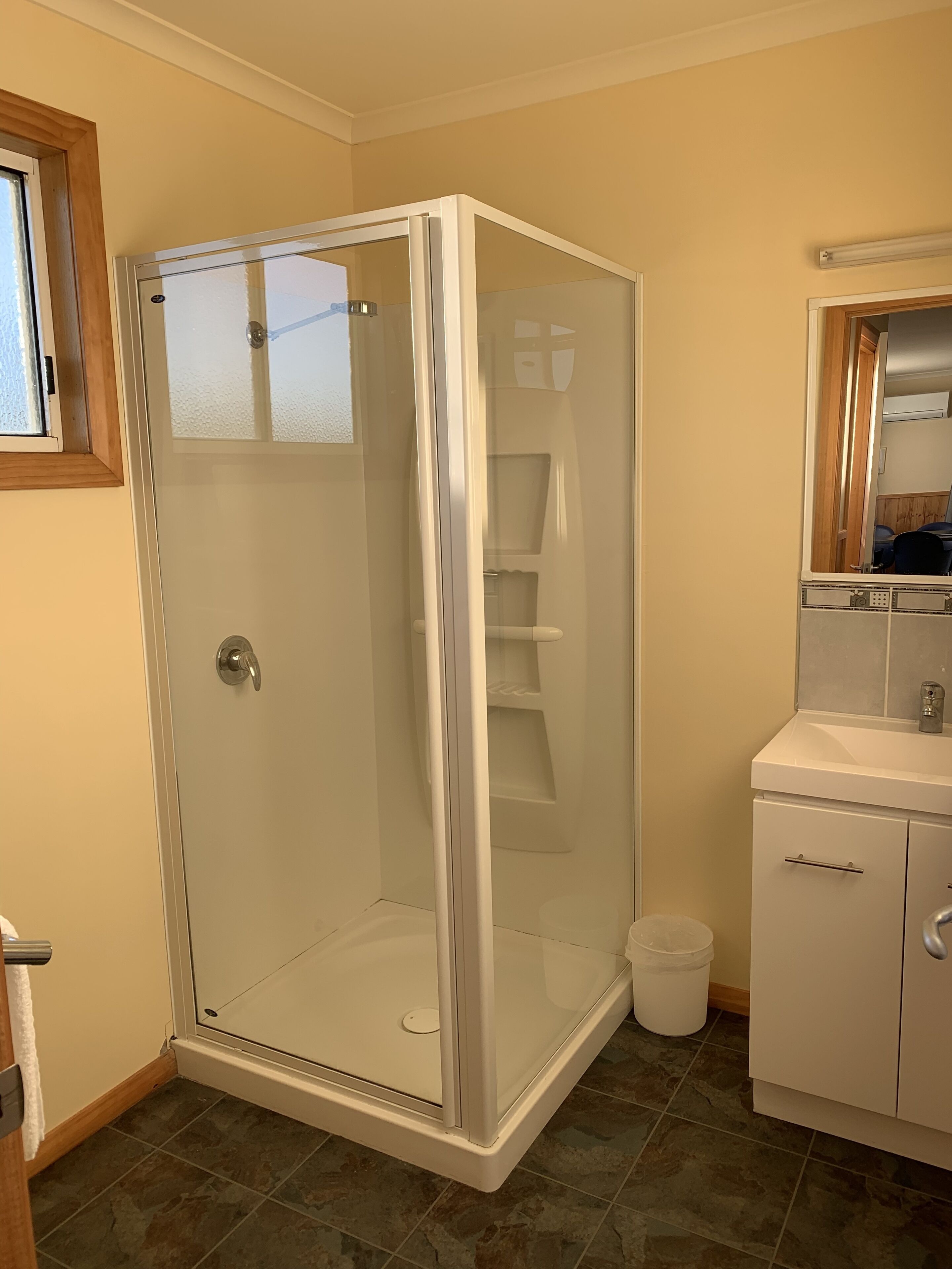 A bathroom with a glass-enclosed shower, a sink, and a mirror.