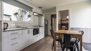 Una cocina moderna con armarios blancos, una mesa de comedor de madera y sillas negras.
