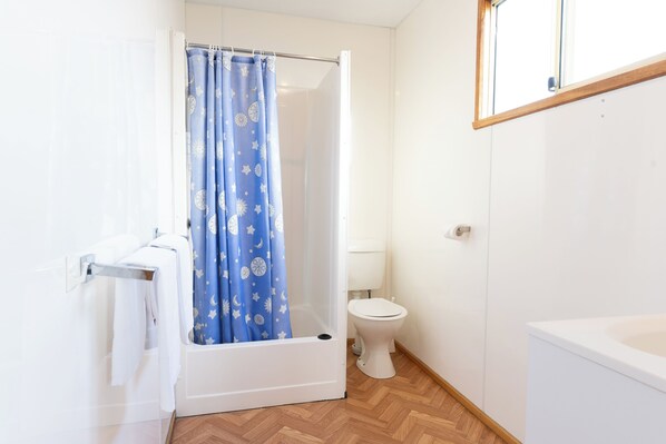 A bathroom with a shower curtain, toilet, and bathtub.