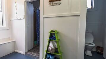 Un baño con un estante verde que contiene artículos de tocador, una cortina de ducha y un letrero en la pared.