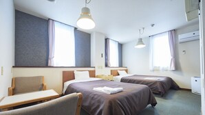 Ein Hotelzimmer mit zwei Betten, einem Schreibtisch, einem Stuhl und einem Vorhangfenster.