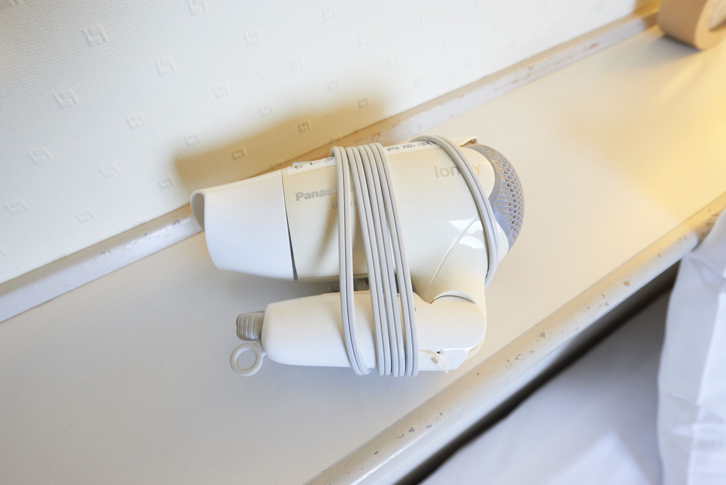 A white device with a cable and a metal component on a white surface.