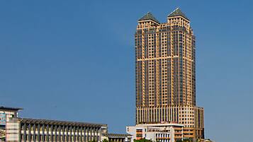 A tall, modern skyscraper with a unique architectural design, situated by a waterfront.