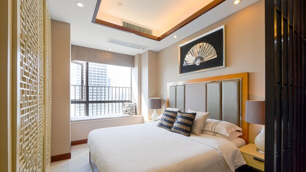Ein Hotelzimmer mit einem großen Bett, zwei Nachttischen, einem Fenster mit Blick auf die Stadt und einem dekorativen Wandbild.