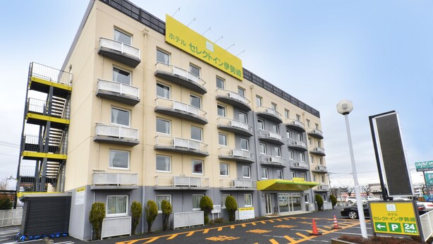 Ein mehrstöckiges Hotel mit einem gelben Schild, das eine Parkmöglichkeit rund um die Uhr anzeigt.