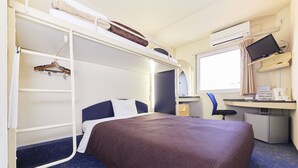 Ein kleines Hotelzimmer mit Etagenbett, Schreibtisch inklusive Computer und einer kompakten Küchenzeile.