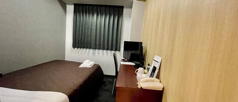 A hotel room with two beds, a desk with a computer, a telephone, and a coffee maker.