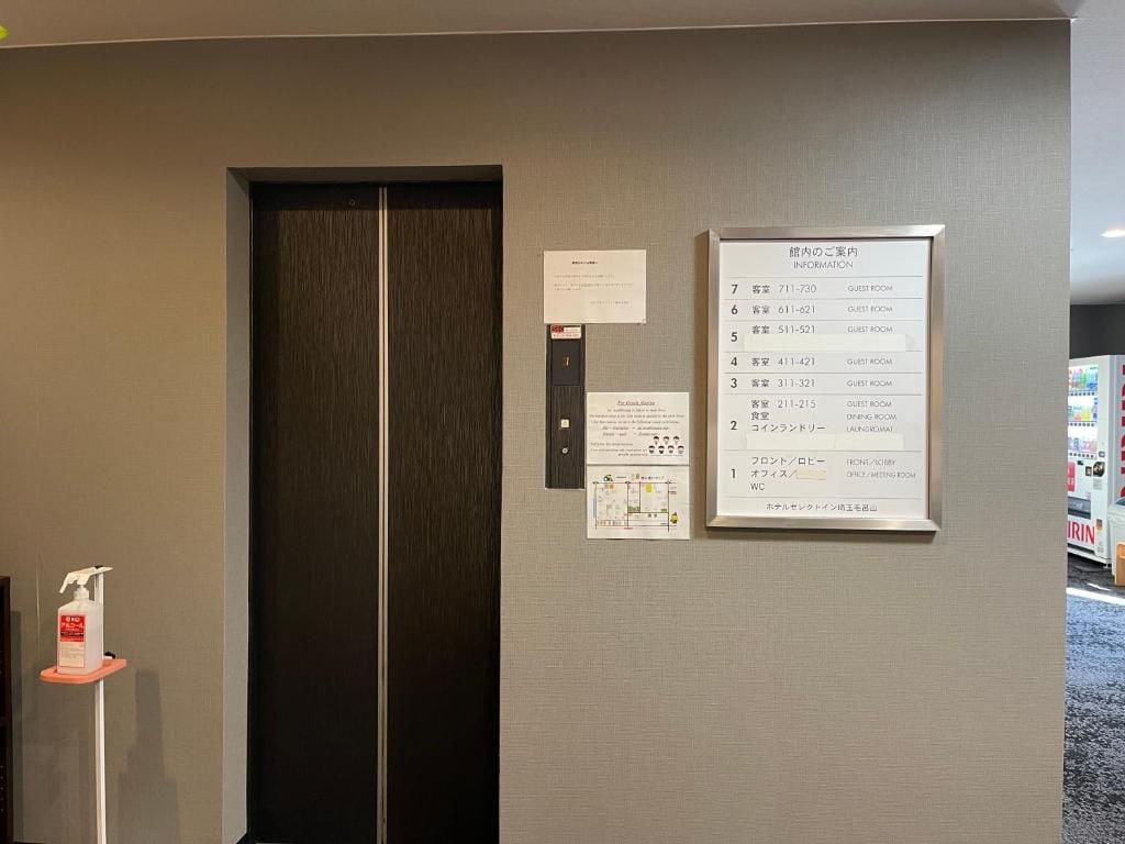 An elevator with a sign listing guest room numbers and a notice about COVID-19 precautions.