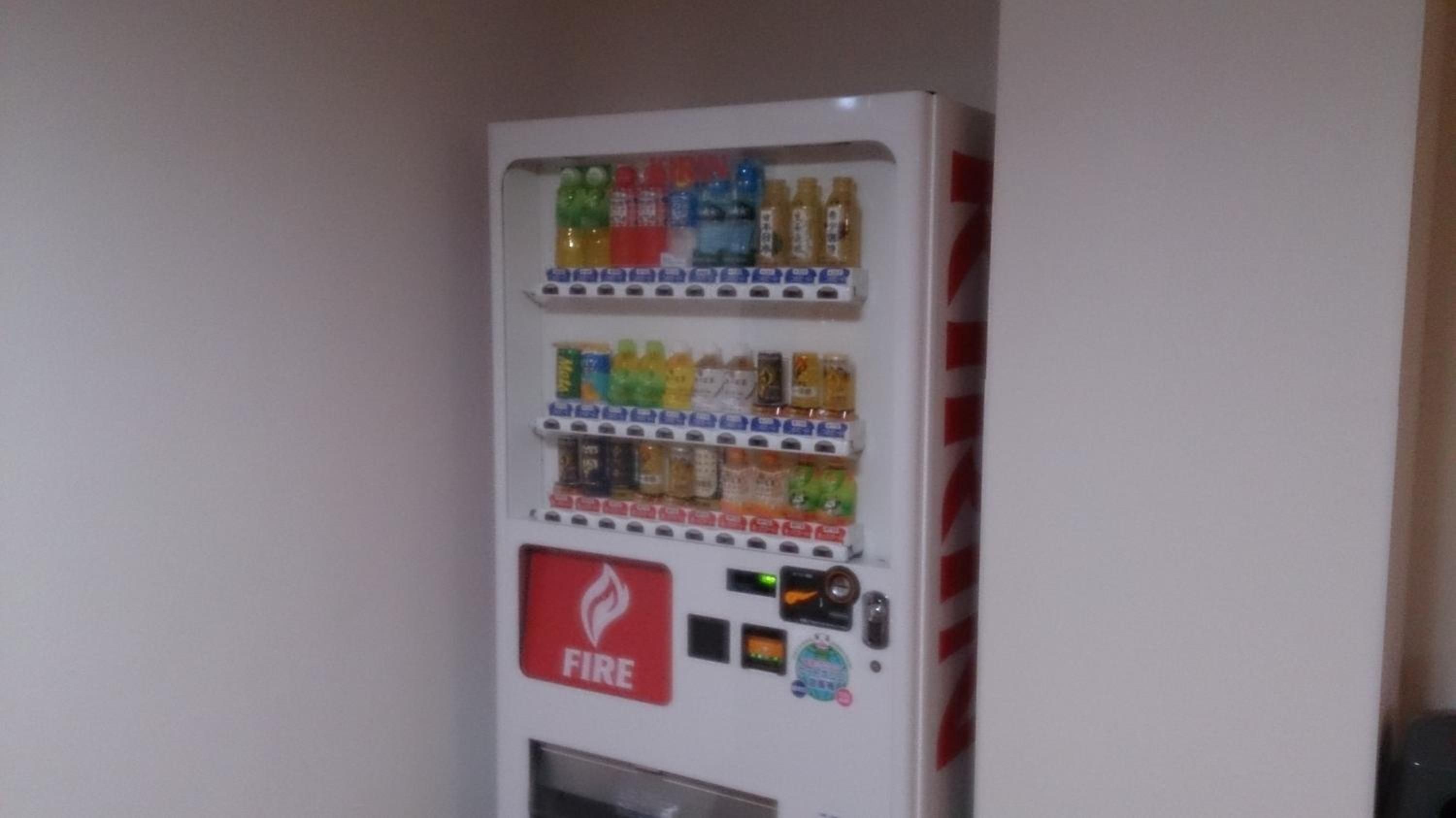 A vending machine with multiple beverage options and a fire extinguisher.