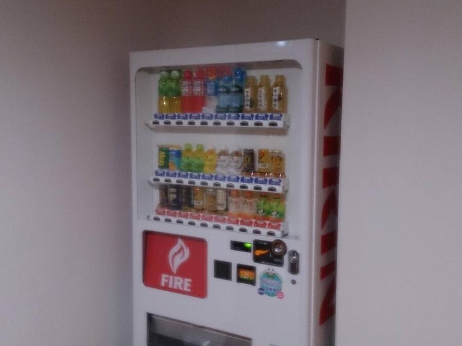A vending machine with multiple beverage options and a fire extinguisher.
