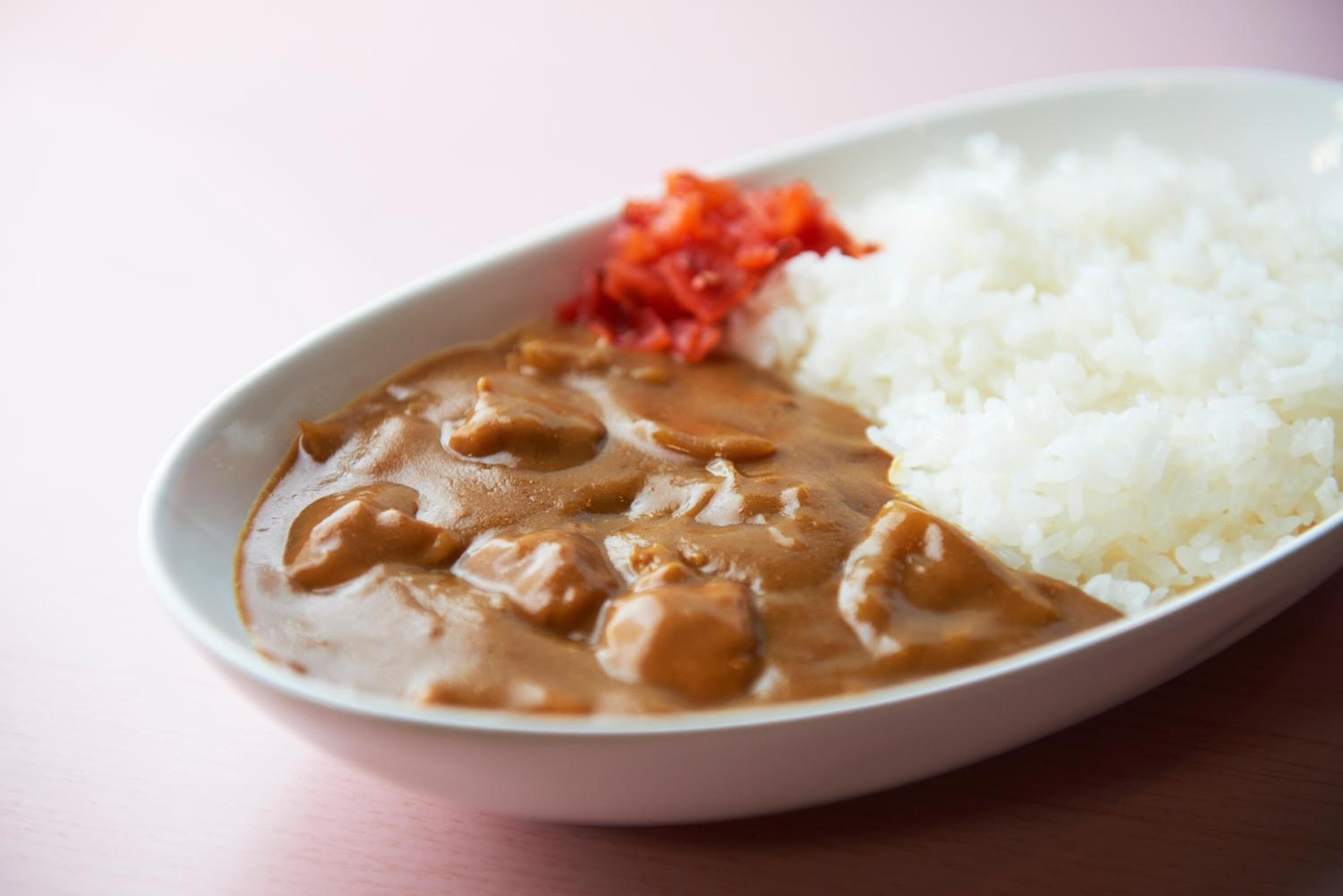 A plate with white rice, a brown sauce, and red pickled vegetables.