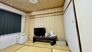 A room with a wooden ceiling, a flat-screen TV on a dark stand, a small white cabinet, a checkered box, and a trash bin. - Hotel Select Inn Saitama Moroyama (Moroyama)