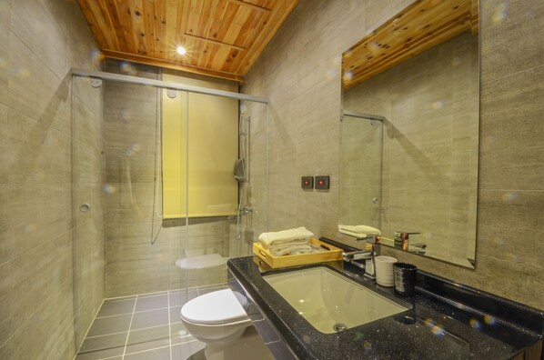 Une salle de bain moderne avec une douche à parois de verre, un lavabo noir et un grand miroir.