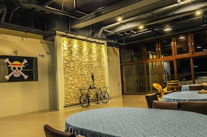 A room with round tables, a stone wall, and a bicycle.