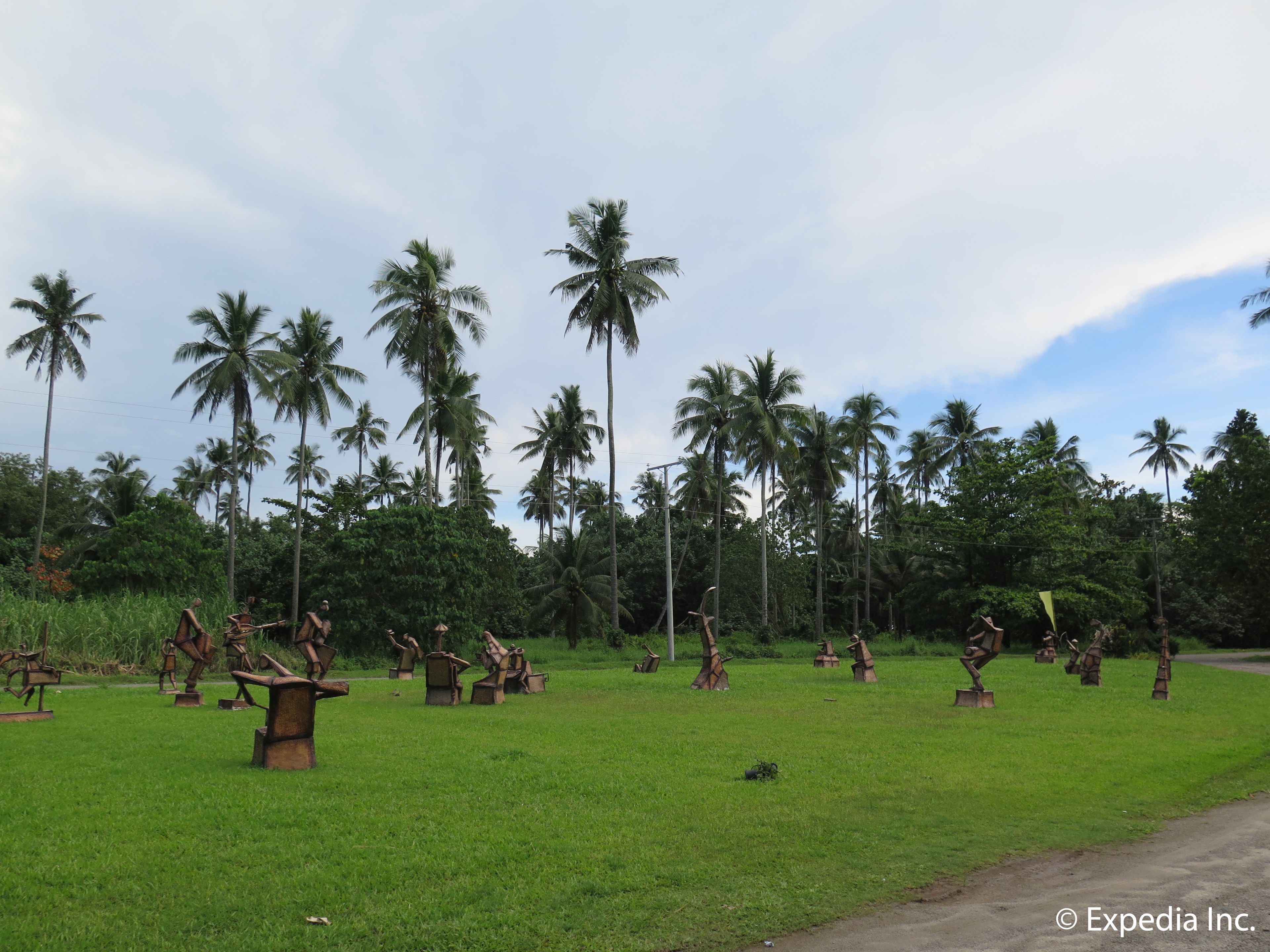 A grassy field with sculptures of animals and a few palm trees in the background.