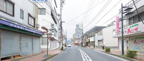 A street view with closed shops, a pedestrian, and a building in the distance.
