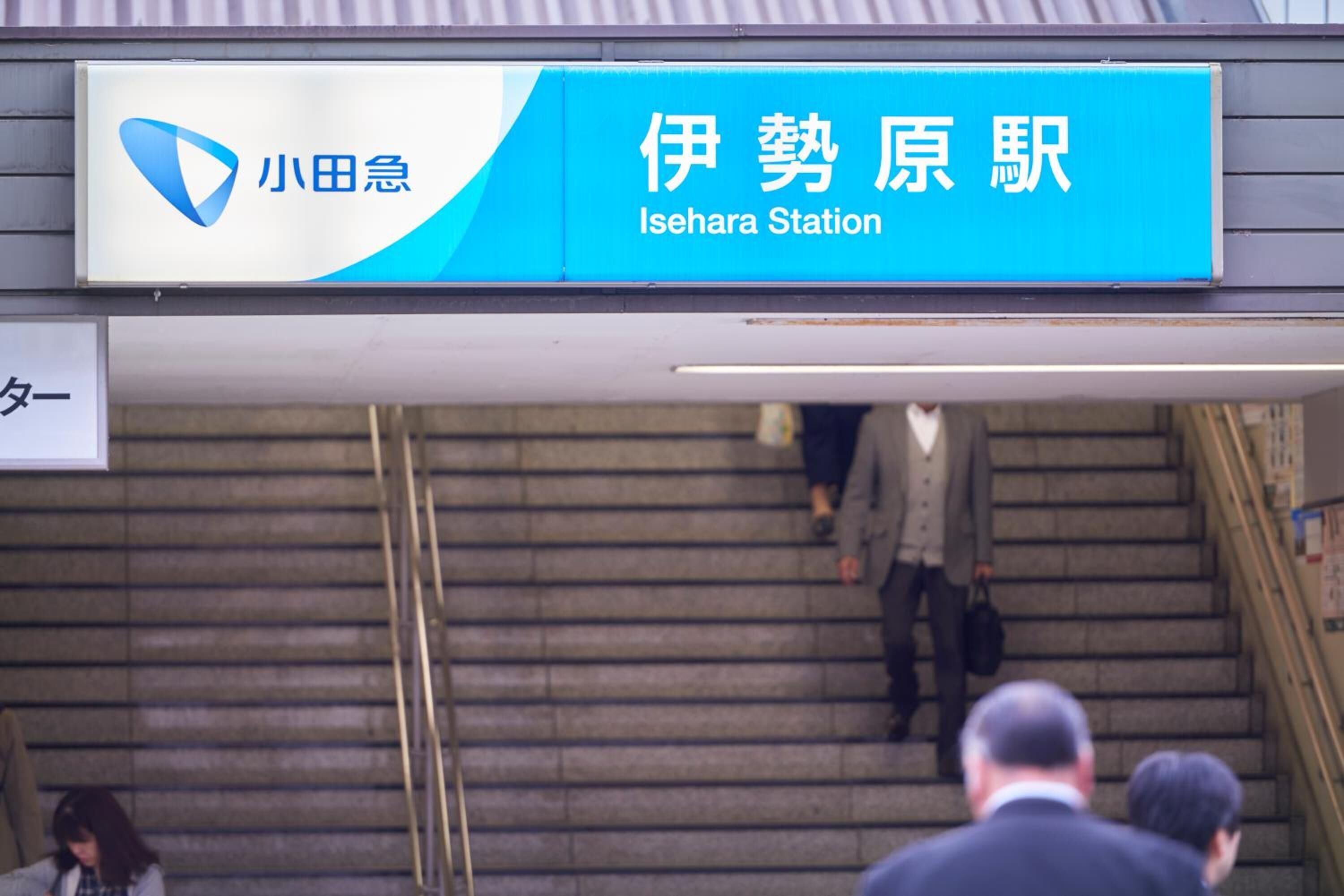 Een stationsbord met Japanse karakters en de Engelse vertaling 'Isehara Station'.