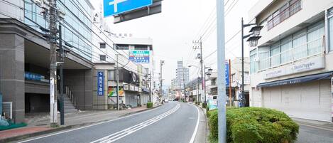 A street with a blue directional sign, buildings, and a bush.