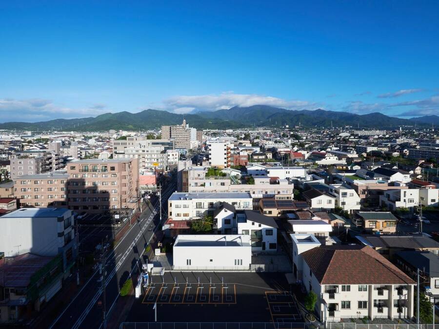 A cityscape with a mix of residential and commercial buildings, a clear sky, and mountains in the background.