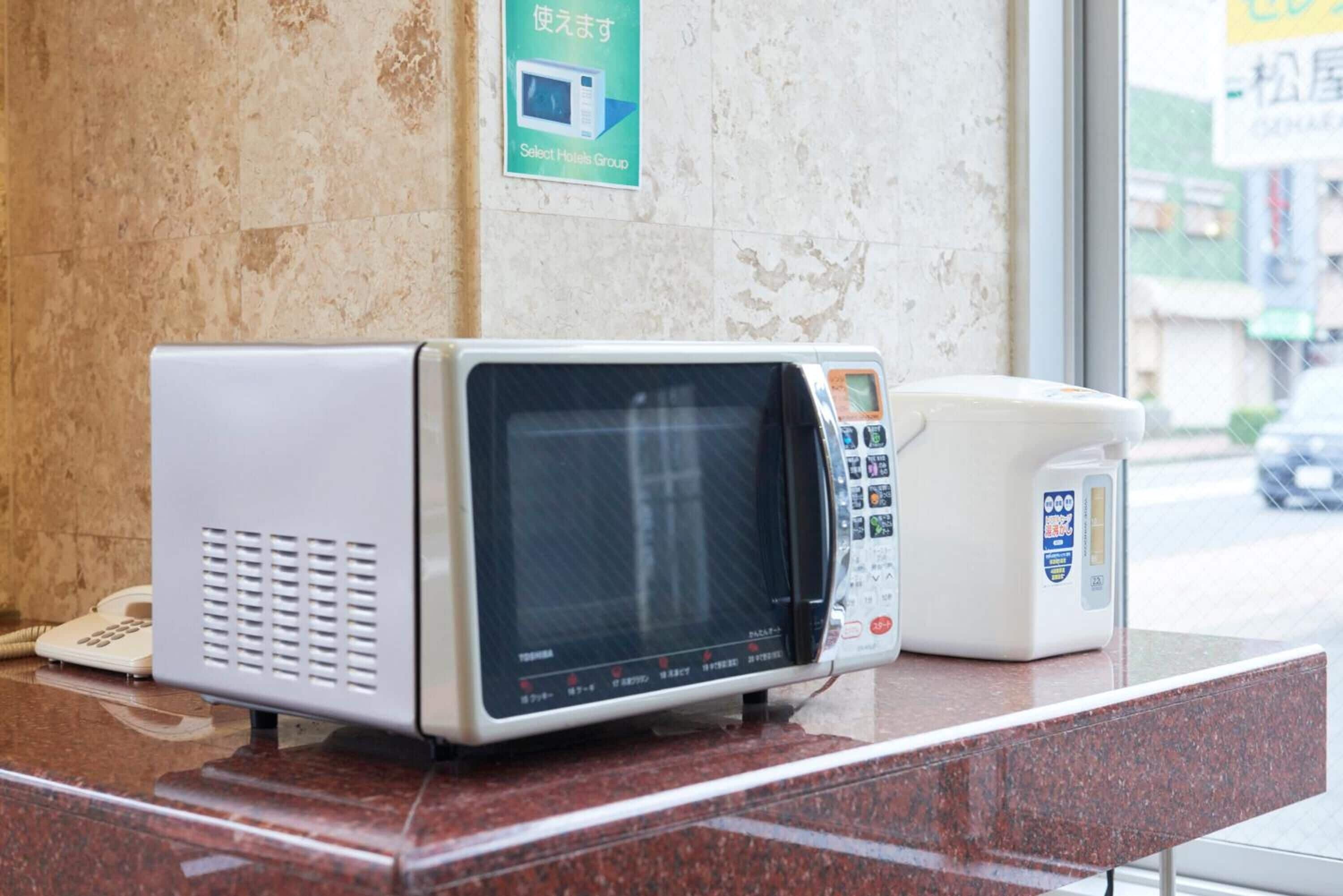 A microwave and a coffee maker on a countertop in a hotel room.