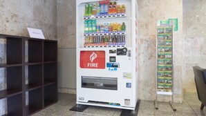 A vending machine with a 'FIRE' logo, various beverages, and a display stand with brochures. - Hotel Select Inn Isehara (Isehara)