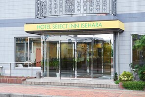 Exterior del Hotel Select Inn Isehara con diseño moderno, que presenta grandes puertas de vidrio y un letrero amarillo.