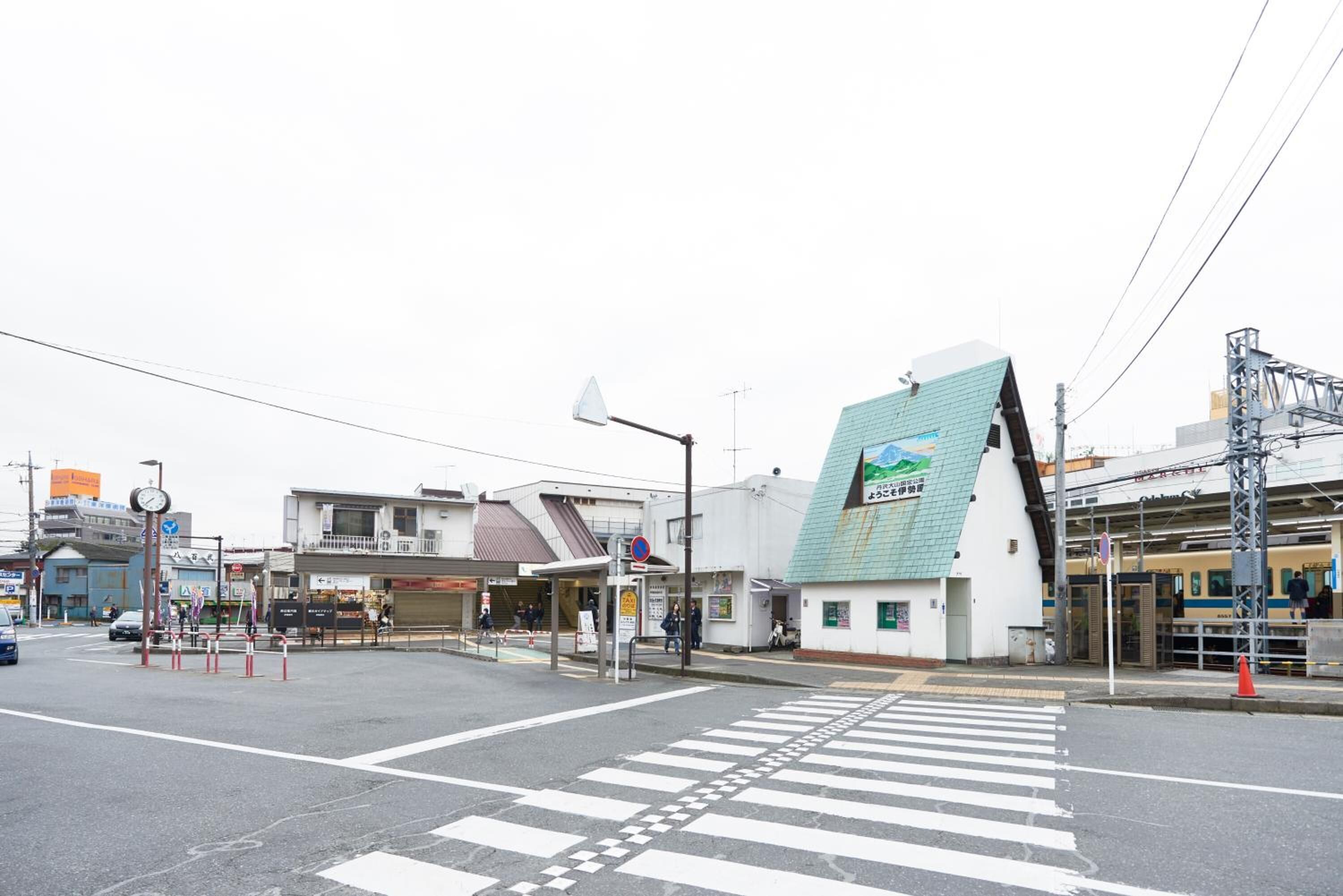 Una intersección con paso de peatones, edificios y andén de estación de tren.