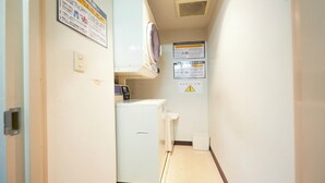 A narrow hallway with a small laundry area, including a washing machine and dryer, and several informational signs on the walls. - Hotel Select Inn Yaizu Ekimae (Yaizu)