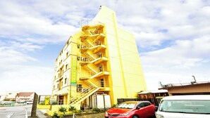 A yellow building with multiple floors and a staircase on the side. - Hotel Select Inn Yaizu Ekimae (Yaizu)