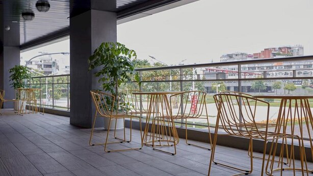 An outdoor seating area with metal chairs and a potted plant, overlooking a cityscape.