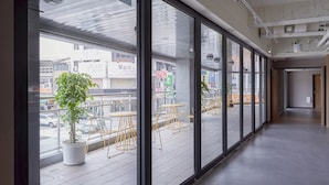 A corridor with large windows, potted plants, and outdoor seating.