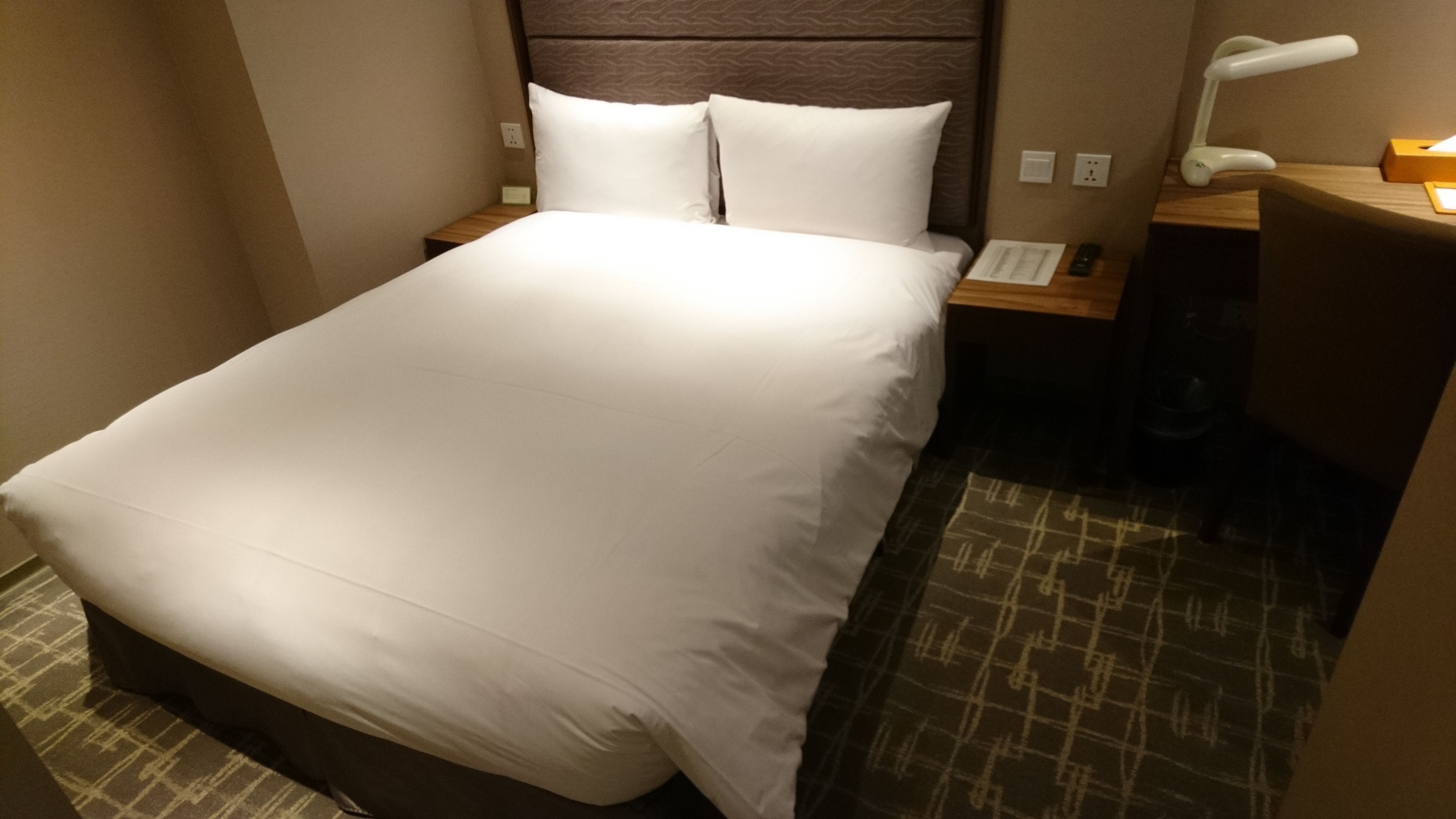 Una cama bien hecha con ropa blanca en una habitación de hotel.
